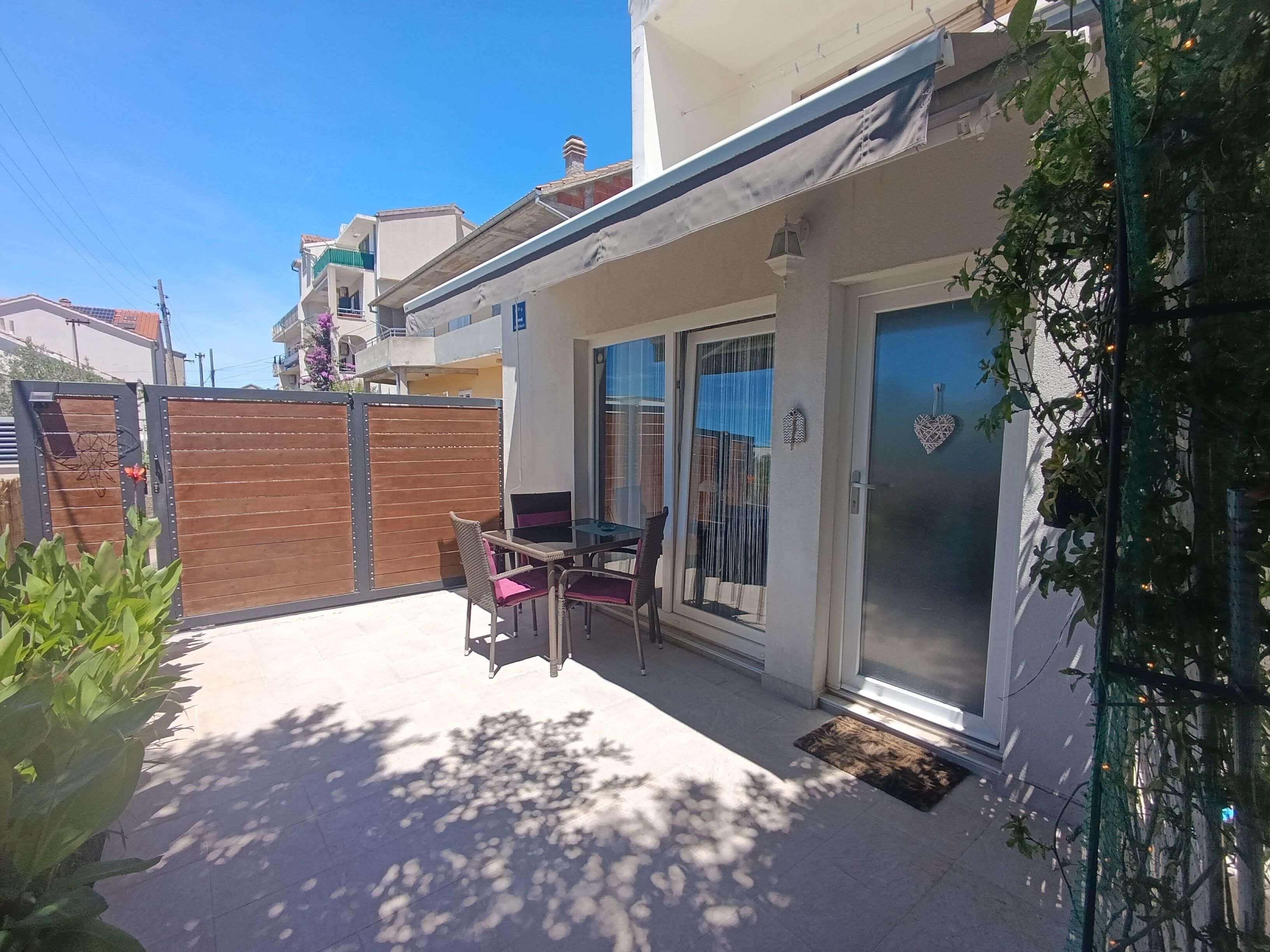A residential property with a patio area, a sliding glass door, and a view of neighboring buildings.
