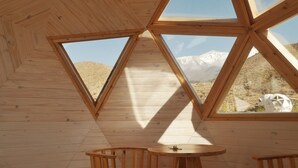 A wooden cabin with a triangular roof and large windows offering a view of a snow-capped mountain. - Domos Andinos HostCamp  (Potrerillos)
