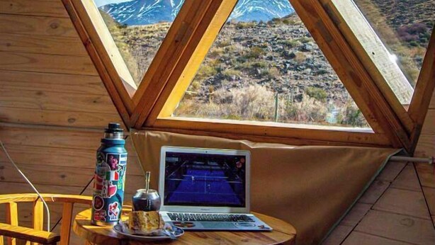 A cozy room with a laptop on a small table, a chair, and a window with a mountain view. - Domos Andinos HostCamp  (Potrerillos)