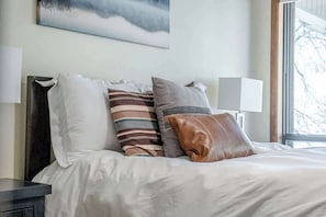 A neatly made bed with a variety of pillows and a bedside table.