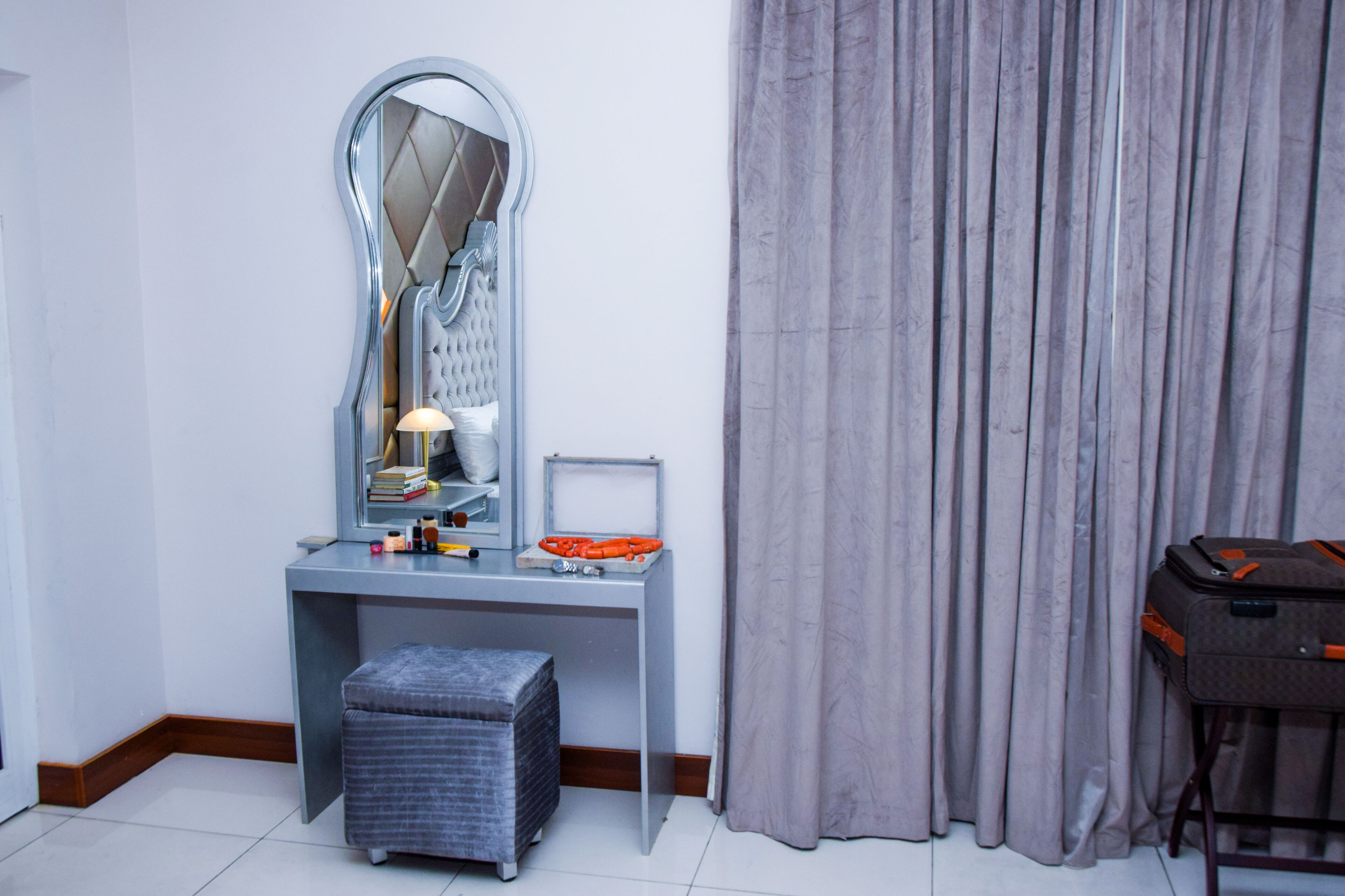 A room with a vanity, mirror, and a suitcase.