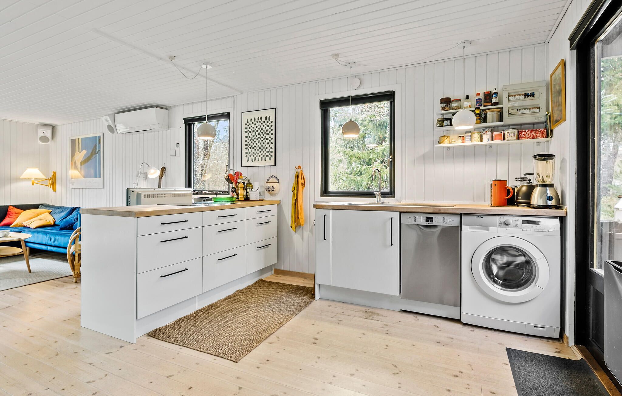 Une cuisine moderne avec des meubles blancs, un lave-linge encastré et une grande fenêtre.