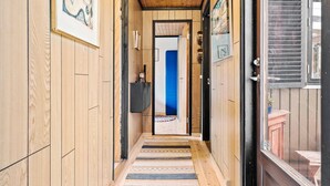 A narrow hallway with wooden walls and a striped rug leading to a door. - 3 bedroom nice home in Vig (Vig)