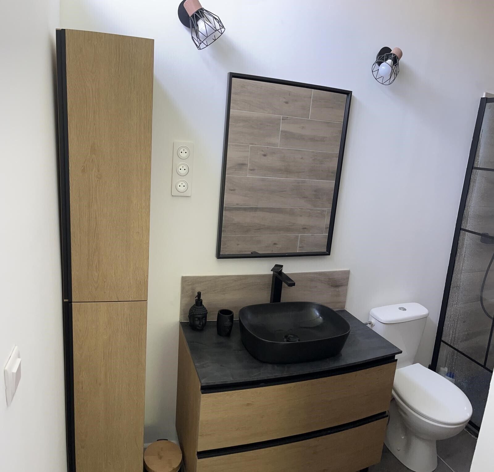 A modern bathroom with a wooden vanity, a black sink, and a toilet.
