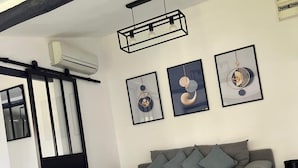 Un salon moderne avec un canapé gris, une table basse blanche et trois œuvres d’art encadrées accrochées au mur.