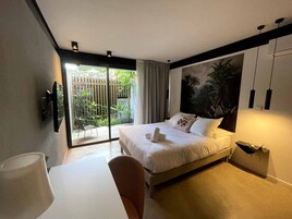 Una habitación de hotel moderna con una cama, un escritorio y vistas a un jardín a través de una puerta corredera.
