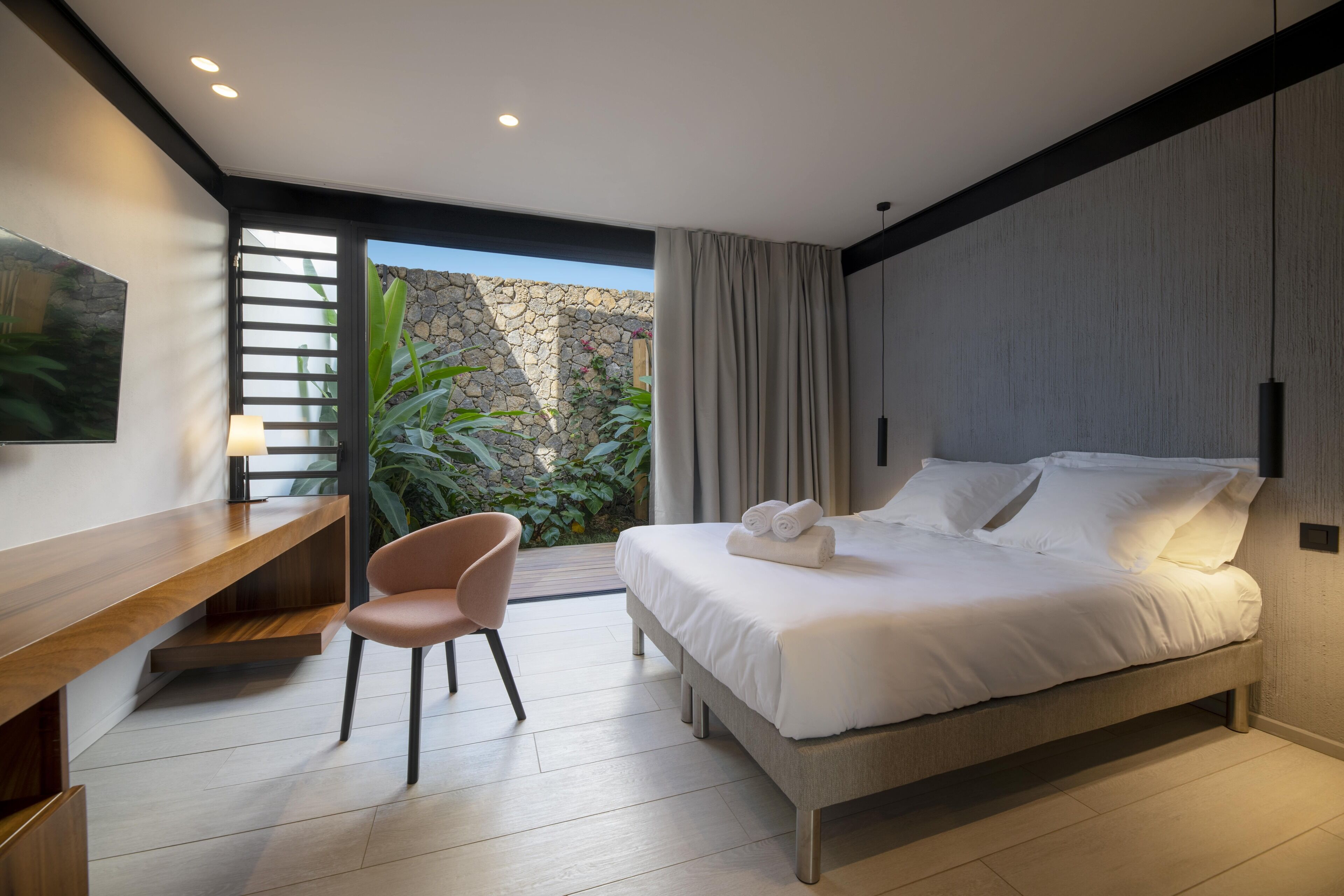 A modern bedroom with a bed, a desk, and a chair.