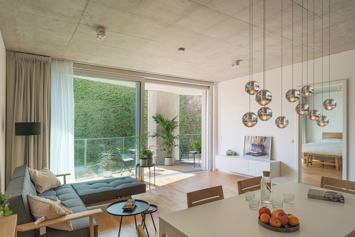 A modern living room with a sofa, dining table, and a large window.