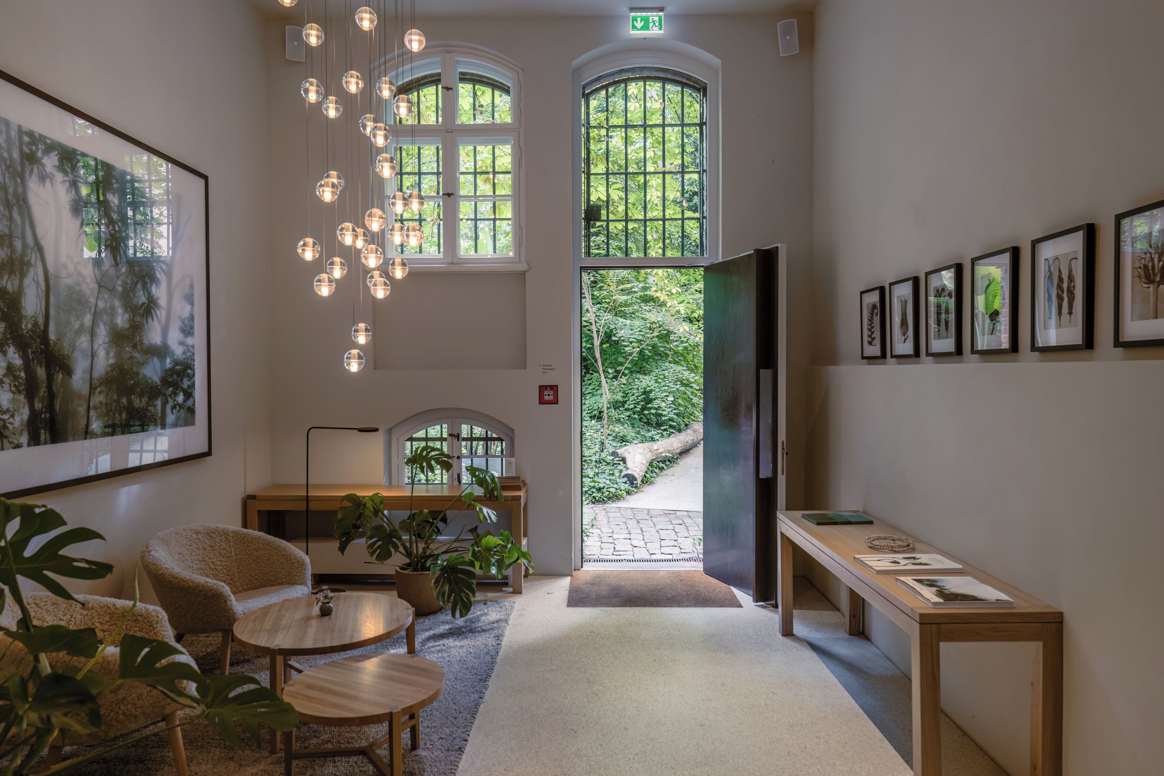 Eine großzügige Lobby mit hoher Decke, mehreren Sitzbereichen, einem Empfangstresen und botanischen Kunstwerken in Rahmen an den Wänden.