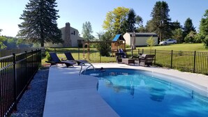 A backyard with a swimming pool, lounge chairs, a covered patio area, and a fenced yard. - Lakefront Escape -1 acre / private pool / kayak / fire pit / swing set (Blakeslee)