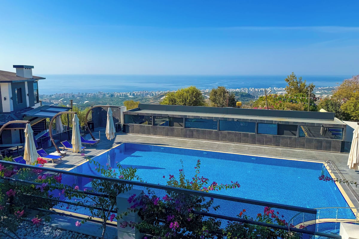 A rooftop pool with a city view, surrounded by greenery and modern architecture.