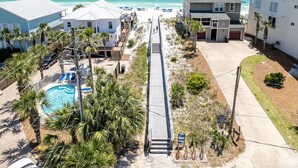 A beachfront property with a swimming pool, a boardwalk, and a view of the ocean.