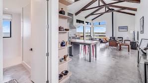 A spacious kitchen with high ceilings and exposed beams, a central island, and a view of the outdoors.