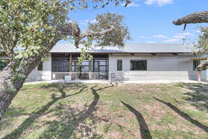 A modern building with a metal roof, large windows, and a grassy lawn. - The Cape 6031e1 1 Bedroom Home by RedAwning (Rockport)