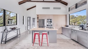 A modern kitchen with a large island, stainless steel appliances, and a view of the outdoors.