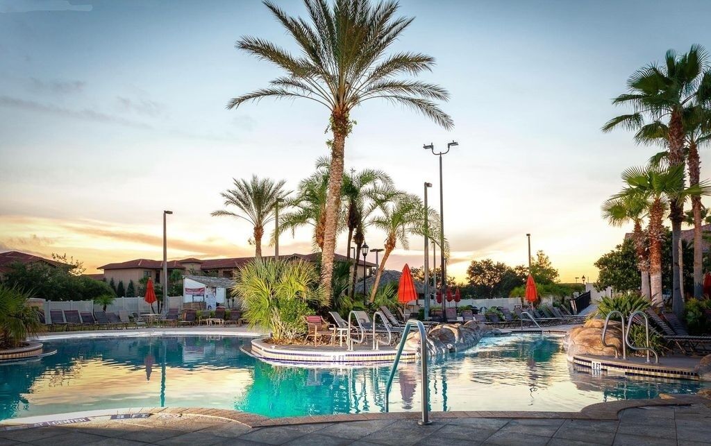 A pool area with multiple pools, palm trees, lounge chairs, and umbrellas.