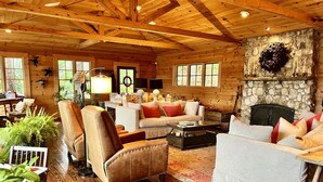 A cozy log cabin interior with a fireplace, wooden floors, and comfortable seating areas. - Luxury Lake Rabun Cabin - restored lakefront w/ stunning views fr/every room! (Lakemont)