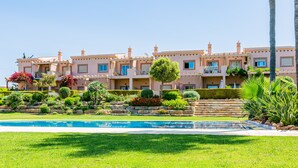 Un hôtel à plusieurs étages doté d’une piscine, de jardins luxuriants et de balcons.