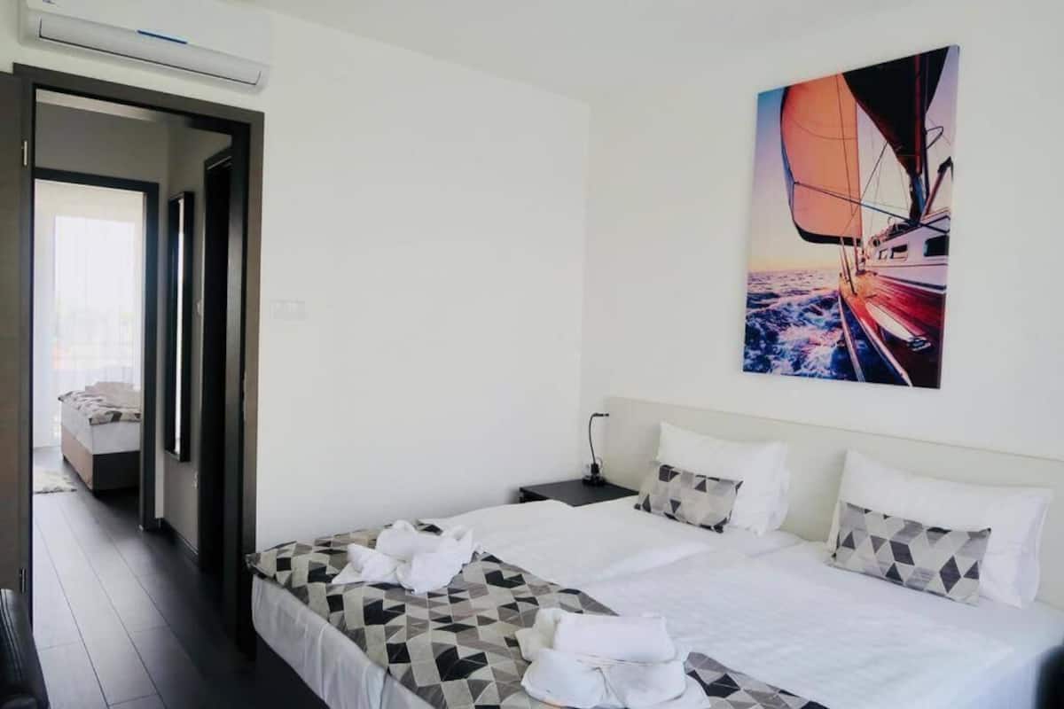 A hotel room with a bed, a nightstand, and a painting of a sailboat on the wall.