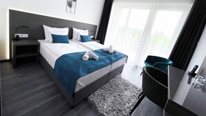 A modern hotel room with a large bed, a desk, and a view of the outdoors. - Hotel Csopak Resort & Lake (Csopak)