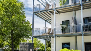 A modern multi-story building with a pool area, outdoor seating, and a well-maintained garden. - Hotel Csopak Resort & Lake (Csopak)