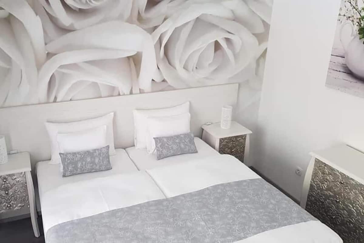 A modern bedroom with a large bed, two nightstands, and a decorative wall panel.
