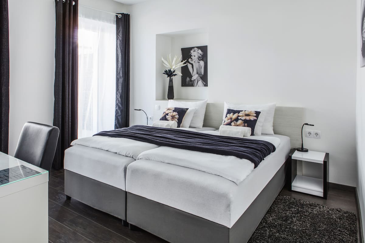 A modern hotel room with a large bed, a desk, and a chair.