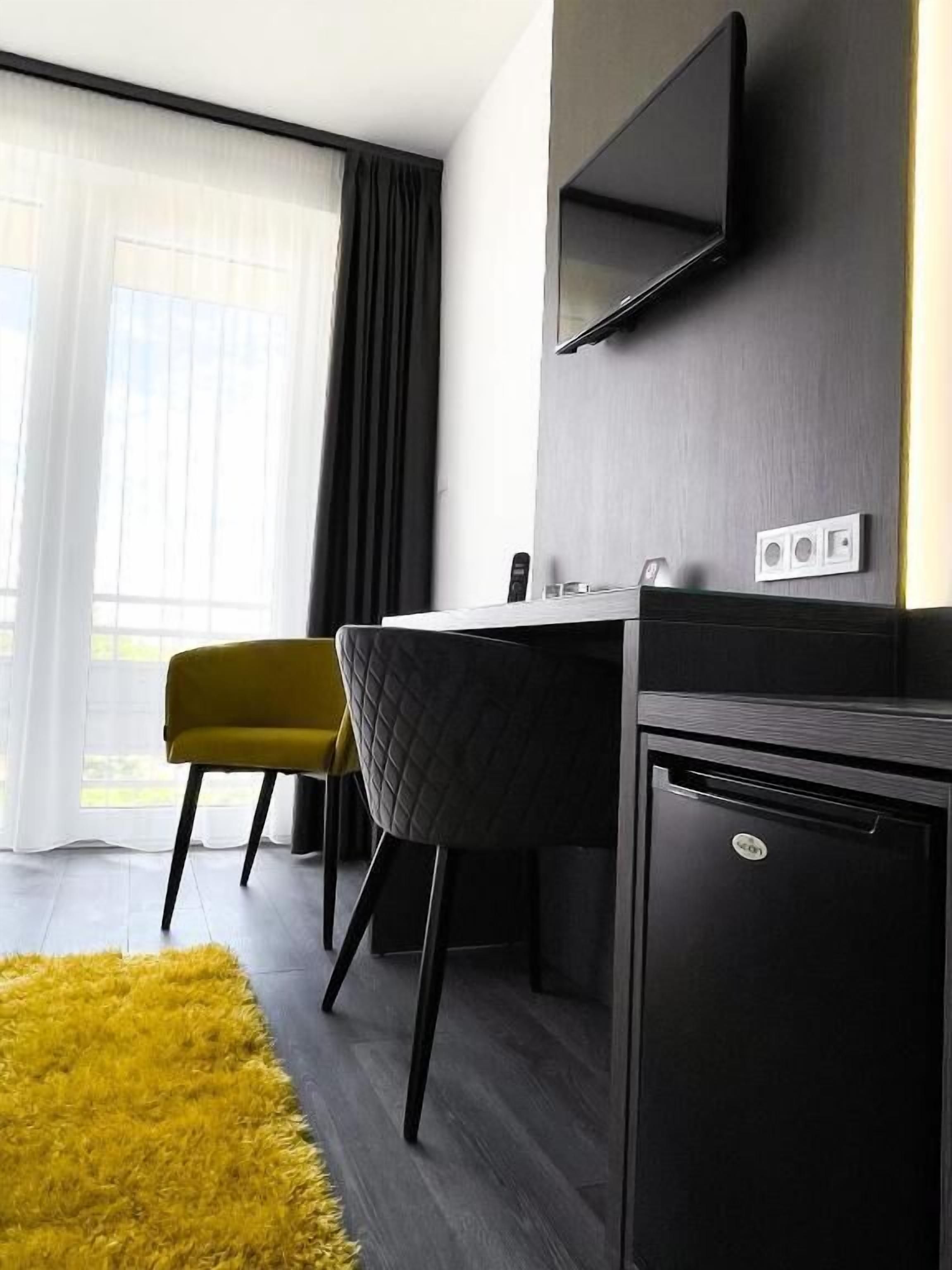 Een moderne kamer met een bureau, stoel en een wandgemonteerde flatscreen televisie.
