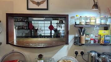 A kitchen counter with a variety of food items, a framed bat picture, and a window with a view of the kitchen.