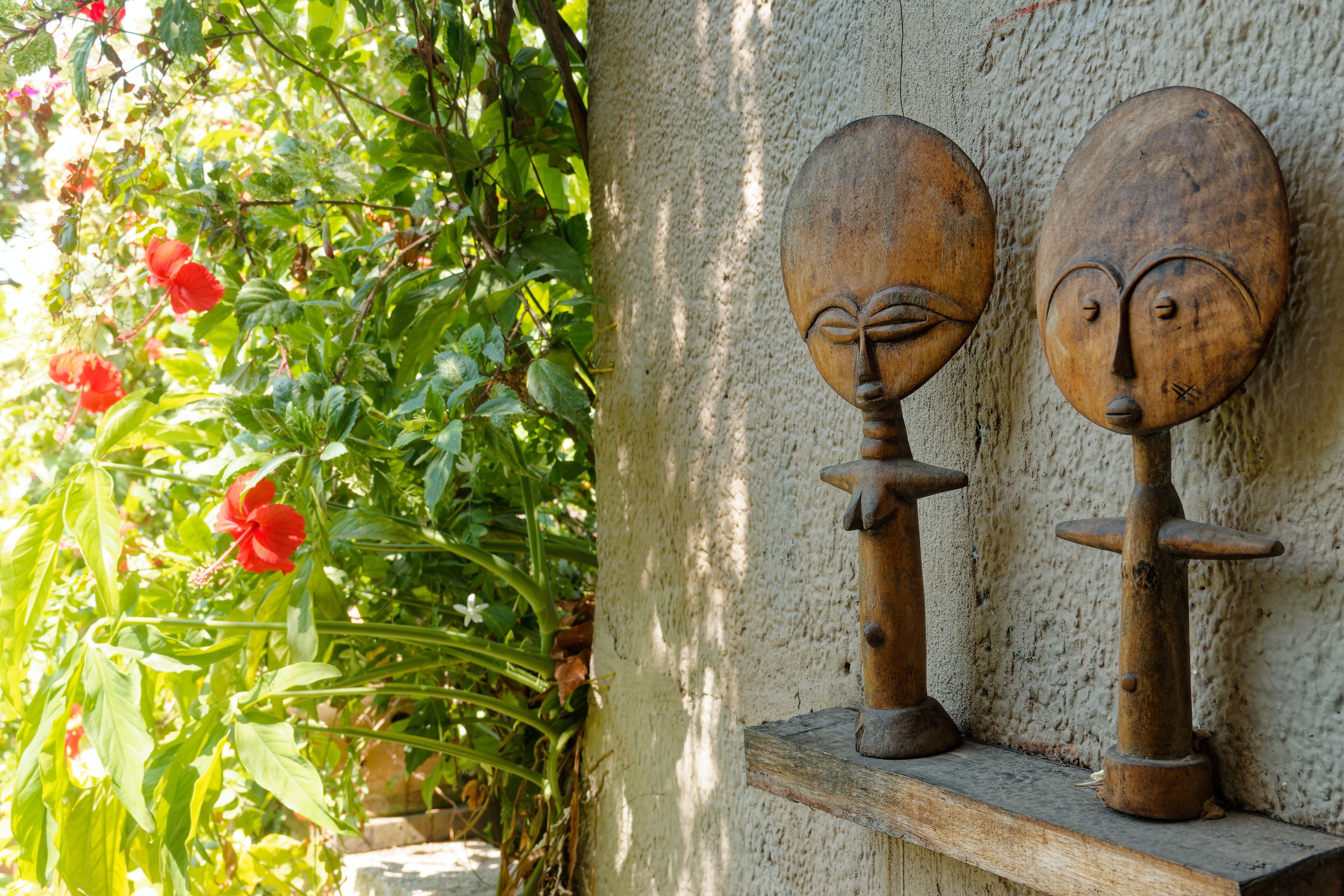 Two wooden sculptures on a shelf against a textured wall.