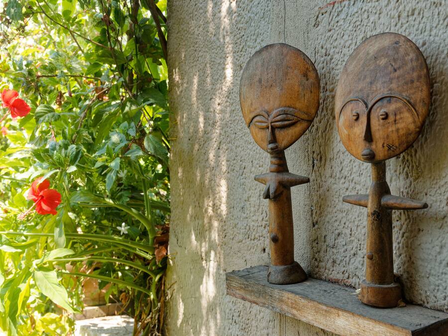 Two wooden sculptures on a shelf against a textured wall.
