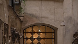 An arched doorway with a geometric pattern, flanked by stone walls with decorative elements. - Cesarina Home   Campo dei Fiori (ROMA)
