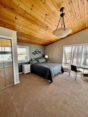 A bedroom with a wooden ceiling, a bed, a desk, and a window with blinds. - Skeet's Retreat: Lake Herman's Hidden Gem of Adventure and Relaxation! Sleeps 8 (Madison)