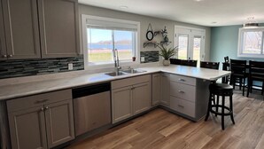 A modern kitchen with a large island, built-in appliances, and a view of the outdoors.