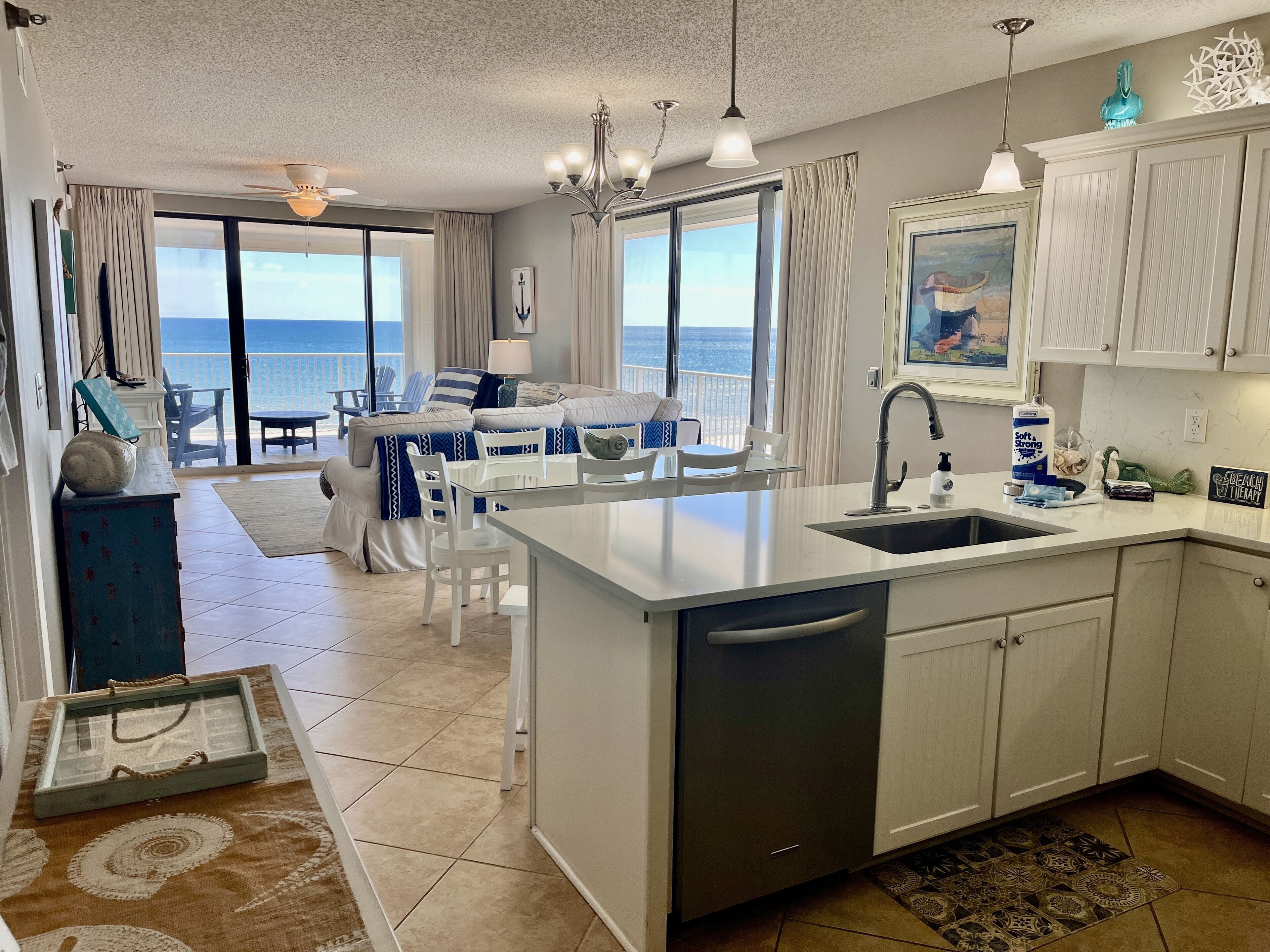 A modern kitchen with a central island, white cabinetry, and a view to the outside.