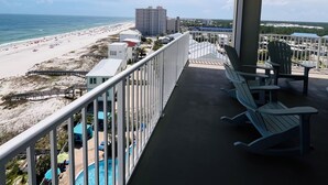 Ein Balkon mit Blick auf einen Strand, ein Schwimmbad und ein Gebäude in der Ferne.