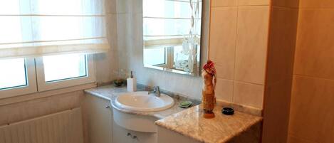 Un baño con ventana, lavamanos, espejo y barra para toallas.