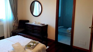 Ein Hotelzimmer mit Bett, Schminktisch, Spiegel und einer Tür zum Badezimmer.