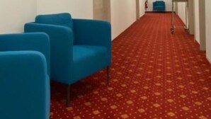 A hallway with blue chairs, a red patterned carpet, and white walls. - Hotel Continental (Nuremberg)