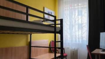 A bunk bed room with a red carpet, a desk with a chair, and a window with curtains.