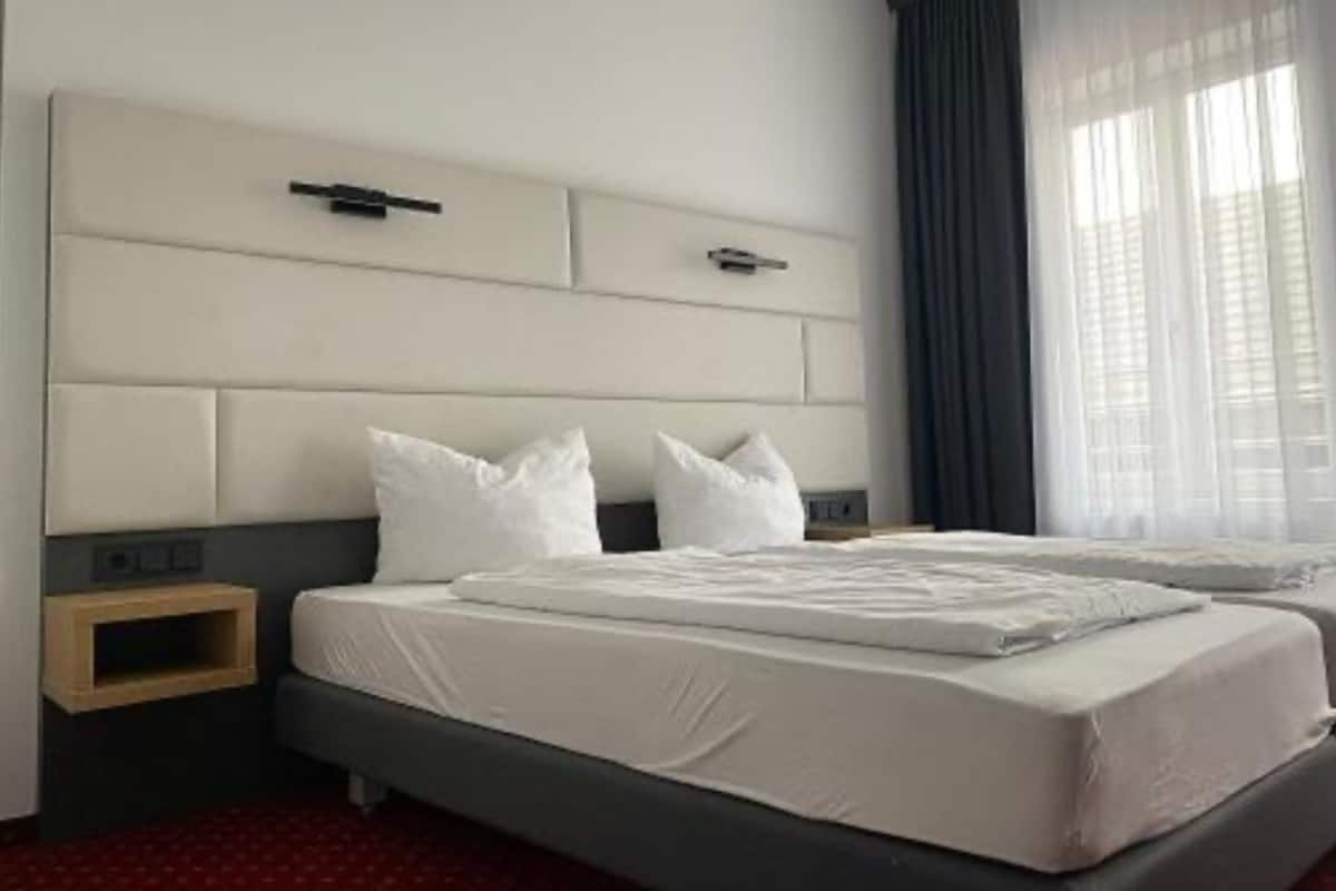 Une chambre d’hôtel avec un grand lit, une table de chevet et une fenêtre avec des rideaux.