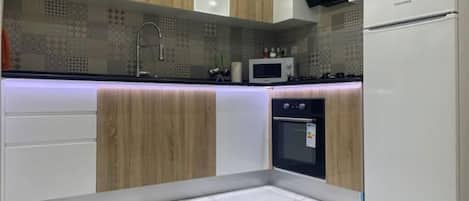 A modern kitchen with wooden cabinets, a built-in microwave, a double oven, and a white refrigerator.
