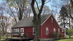 A red wooden house with a porch and a picnic table.
