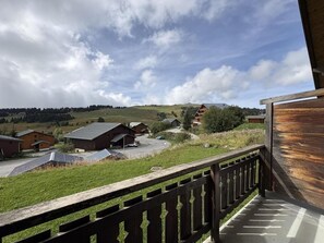 A view from a balcony overlooking a rural landscape with houses and solar panels.