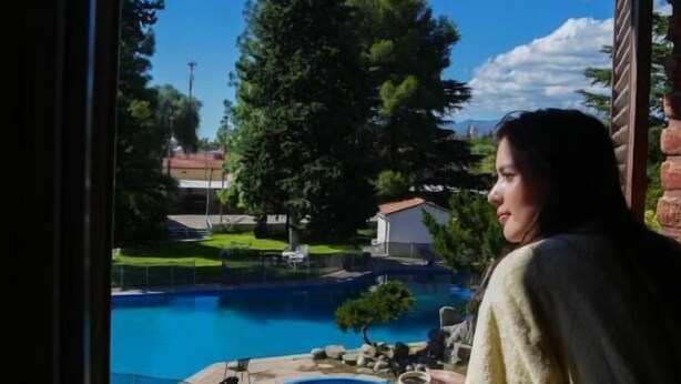 A view of a swimming pool from a window, with a person sitting by the window.
