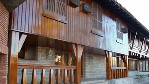 A wooden building with a porch, stone steps, and multiple windows.