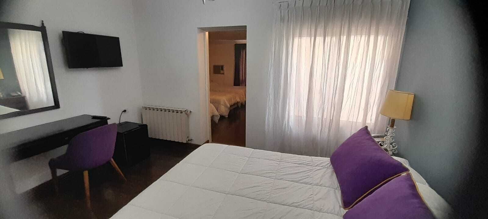 Une chambre d’hôtel avec un lit, un bureau, une chaise, une télévision et une fenêtre avec des rideaux.