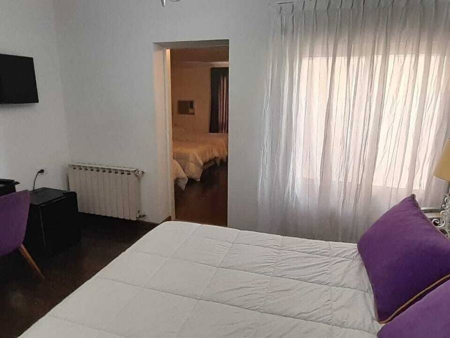 Une chambre d’hôtel avec un lit, un bureau, une chaise, une télévision et une fenêtre avec des rideaux.
