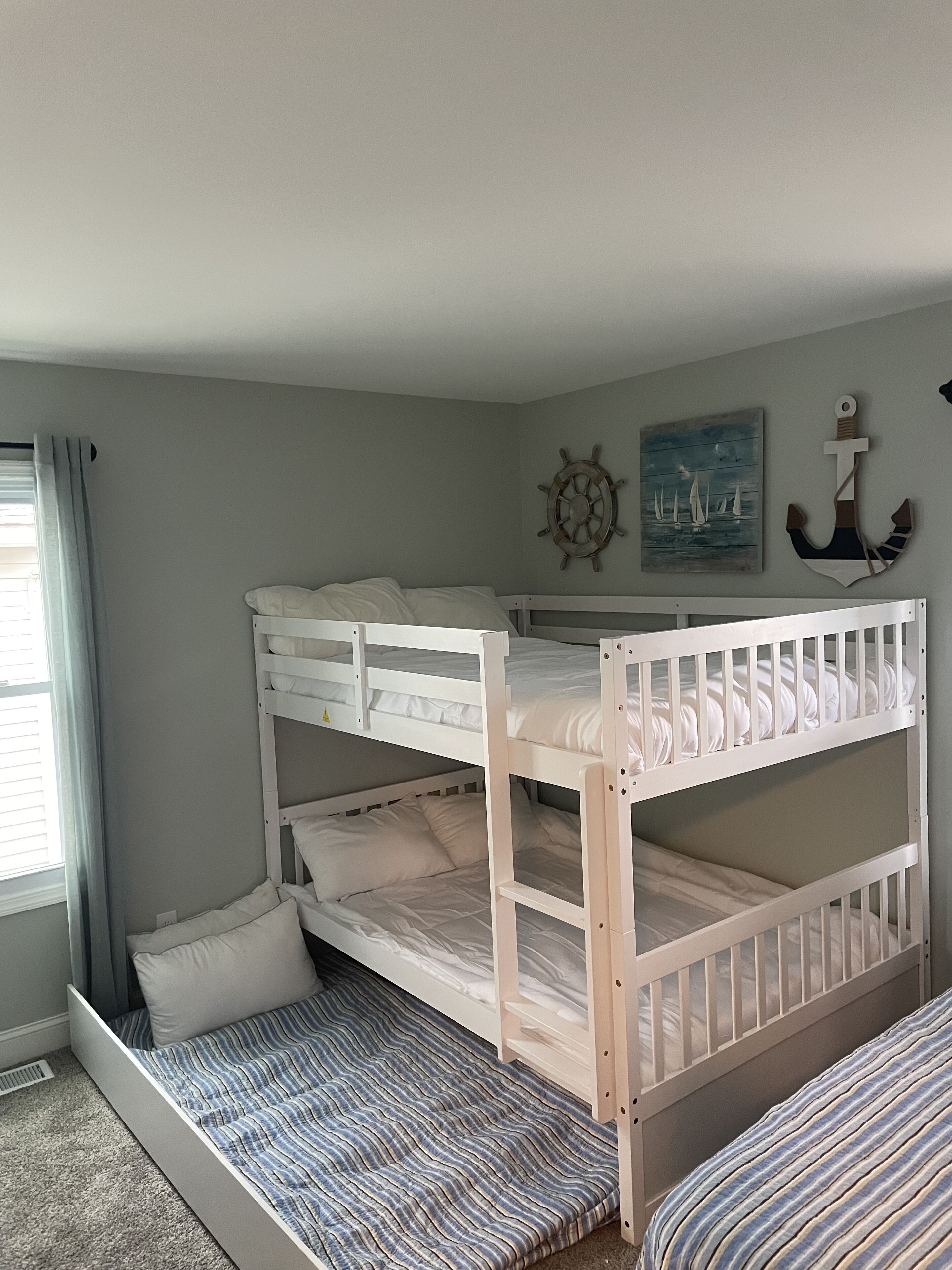 A bunk bed room with a nautical theme, including a ship's wheel and an anchor decoration.