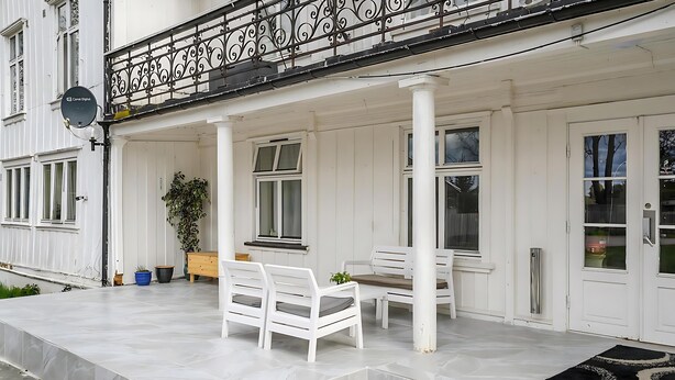 A white building with a balcony, white furniture, and a satellite dish. - Herregårdshuset AS (Ullensaker)